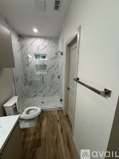 A bathroom with a toilet, sink, and marble wall.