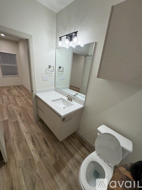 A bathroom with a toilet, sink, and mirror.