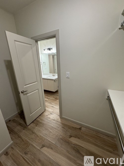 A room with a white door and wooden flooring.