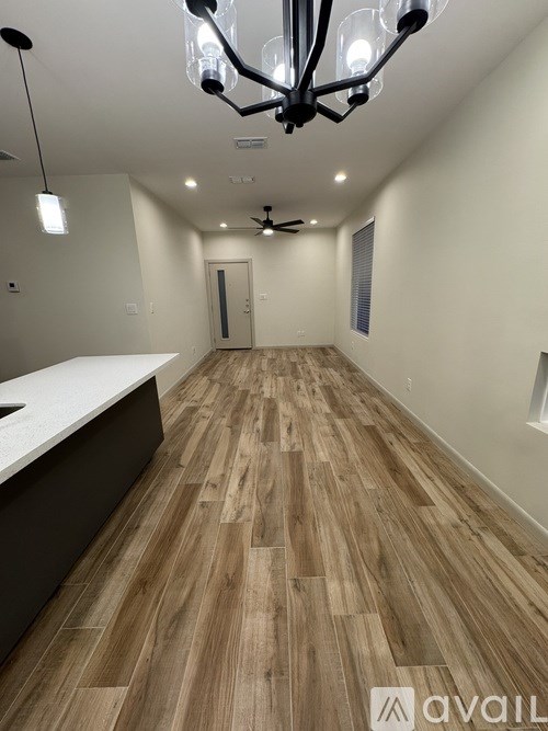A long hallway with wooden floors and a chandelier.