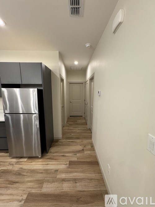 A long hallway with a stainless steel refrigerator on the left.