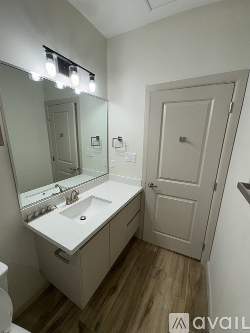 A bathroom with a sink, mirror, and wooden floor.