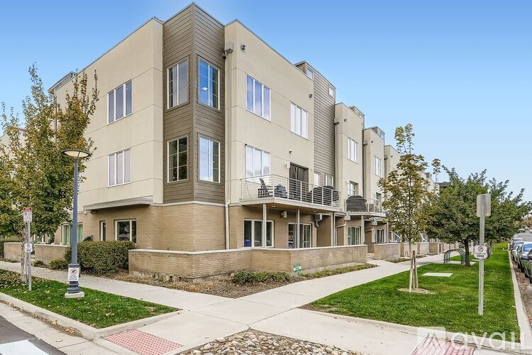 A modern apartment building with a well-maintained lawn in front.