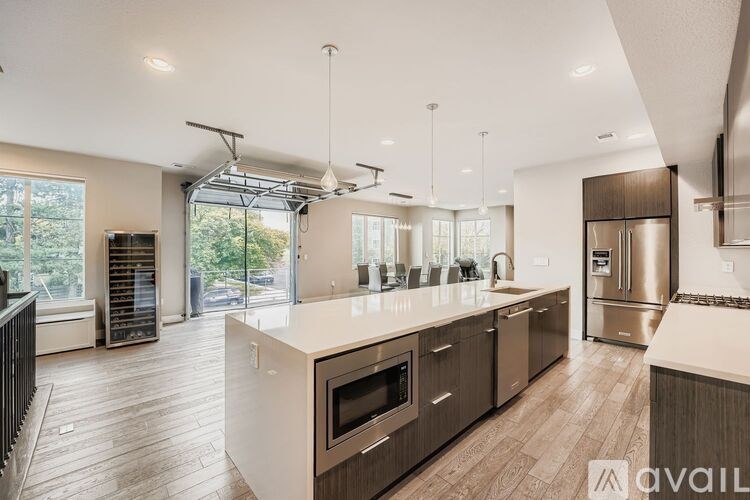 A modern kitchen with wooden floors and stainless steel appliances.