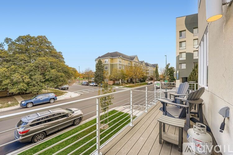 A view from a balcony overlooking a street with cars and buildings.