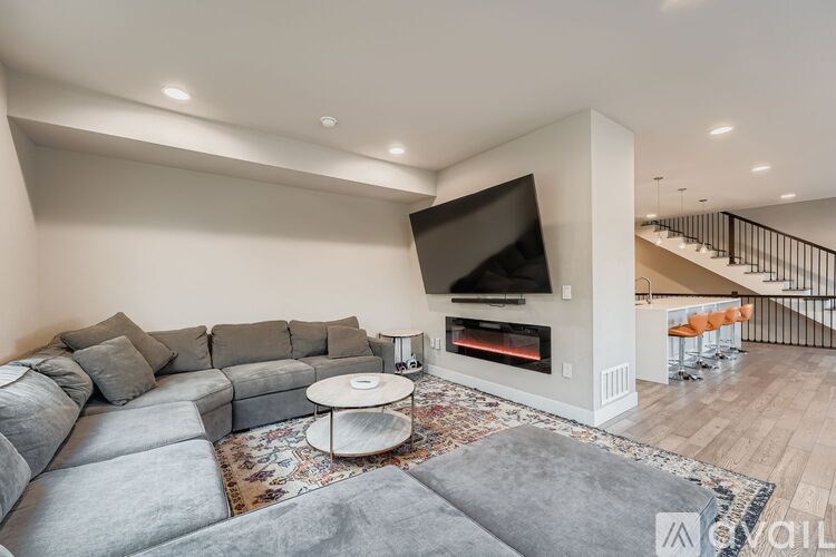 A modern living room with a grey sofa and a television mounted above a fireplace.