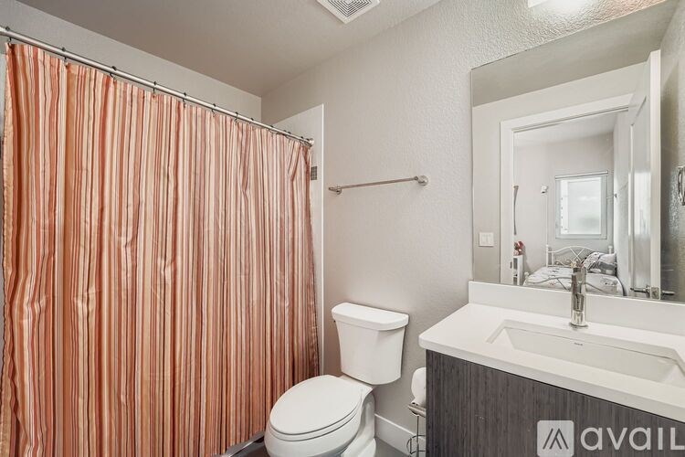 A bathroom with a toilet, sink, and shower curtain.