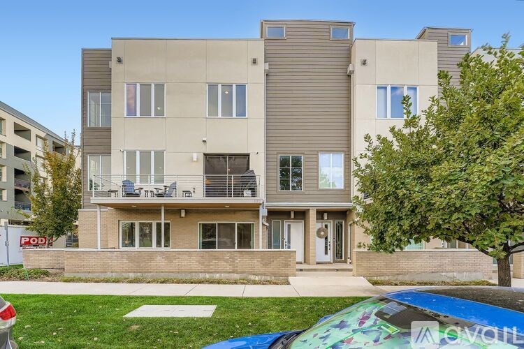 A modern apartment building with a car parked in front.