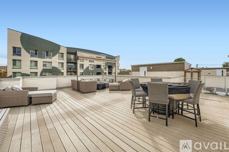 A wooden deck with chairs and a table is in front of a building.