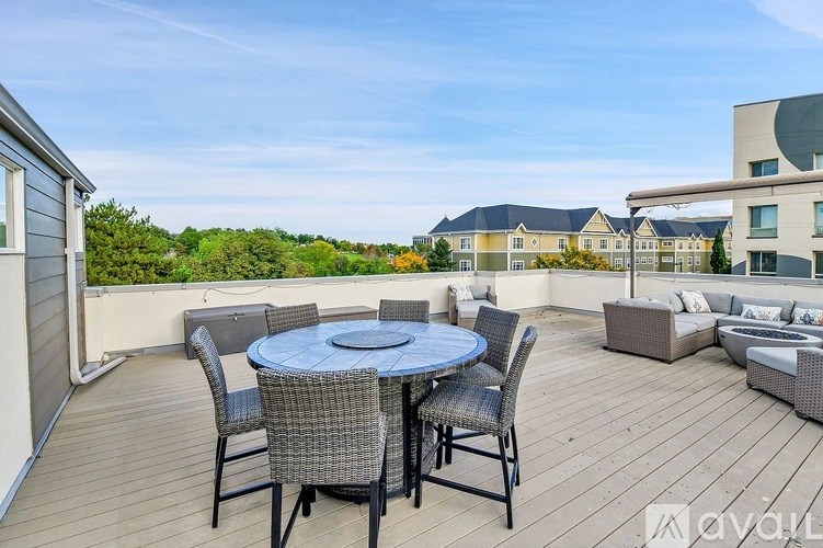 A table with chairs is on a deck with a view of apartment buildings.