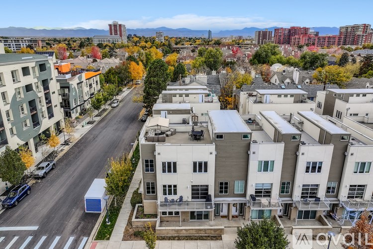 A street view of a residential area with apartment buildings and trees.