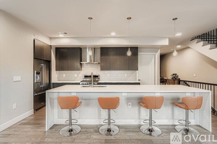 A kitchen with a bar area featuring four bar stools.