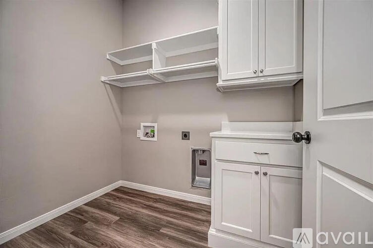 A kitchen with white cabinets and a wooden floor.