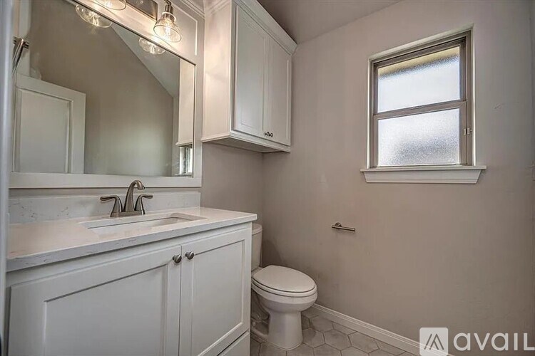 A bathroom with a toilet, sink, and mirror.