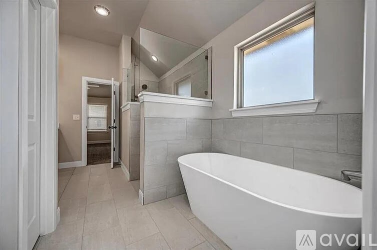 A bathroom with a white tub and a window.