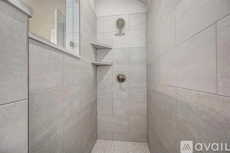 A bathroom with a shower and a white tile floor.