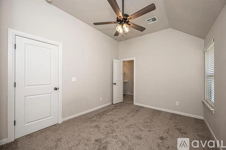 A room with a ceiling fan and carpeted floor.