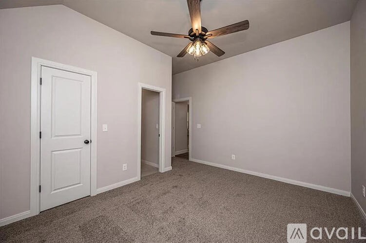 A room with a ceiling fan and carpeted floor.