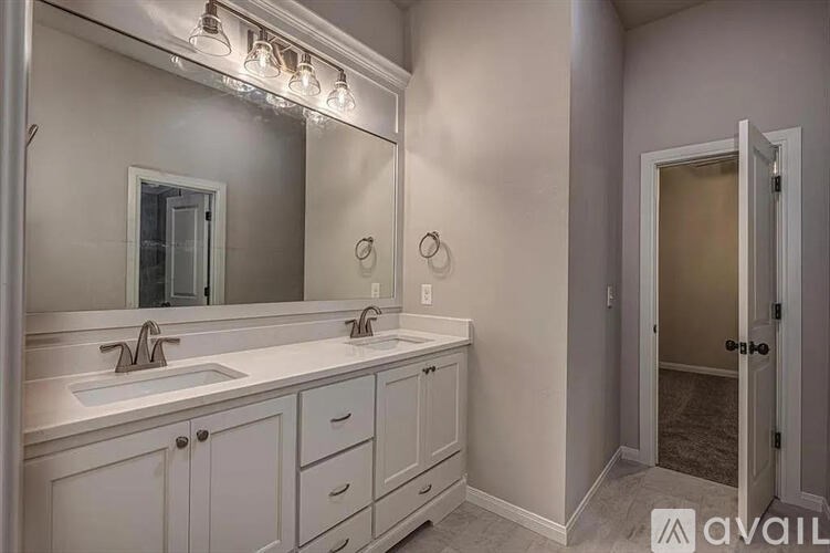 A bathroom with a vanity, sink, mirror, and lighting fixture.