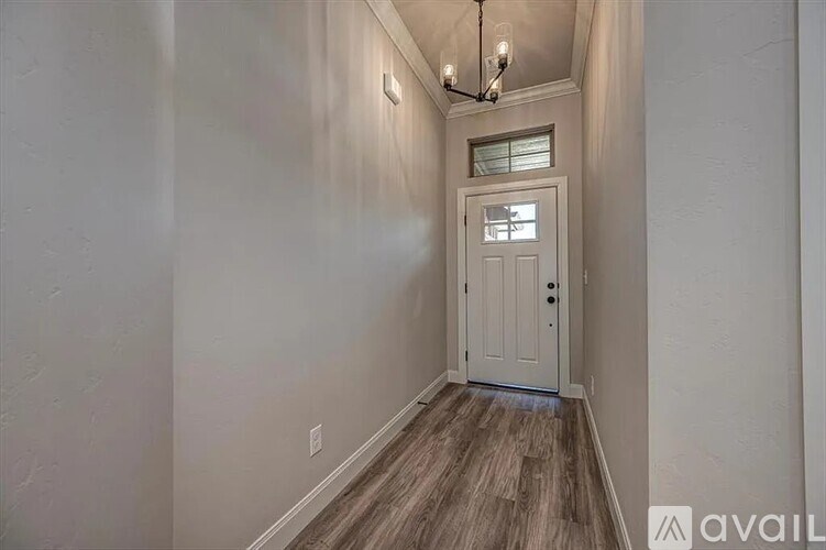 A hallway with a white door and a chandelier.