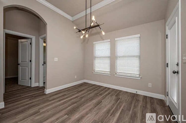 A room with wooden flooring and a chandelier.