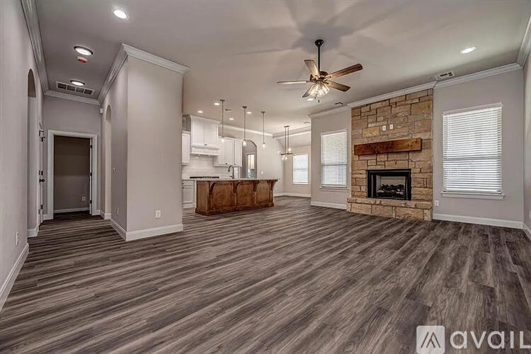 A spacious living room with a fireplace and a ceiling fan.