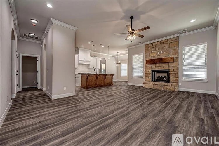 A spacious living room with a fireplace and a ceiling fan.