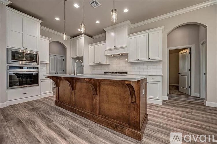 A kitchen with a wooden island and white cabinets.