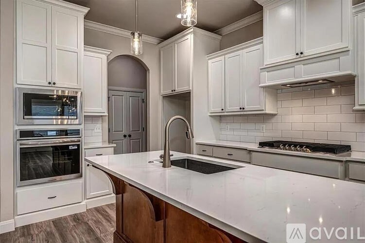 A kitchen with white cabinets and a wooden island.