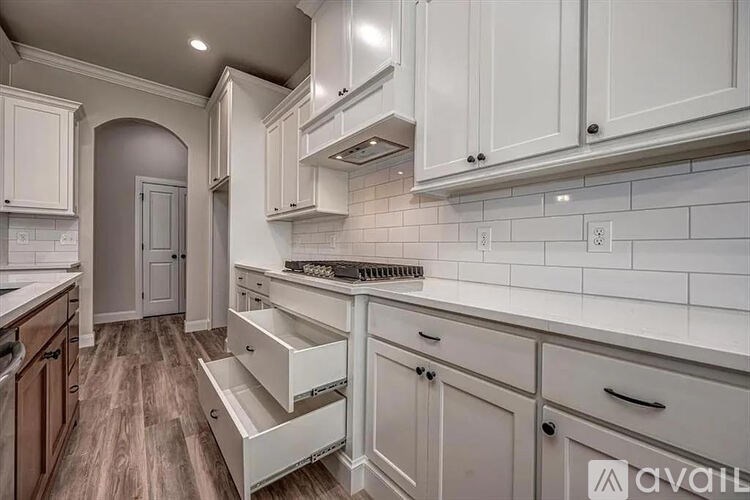 A kitchen with white cabinets and a wooden floor.