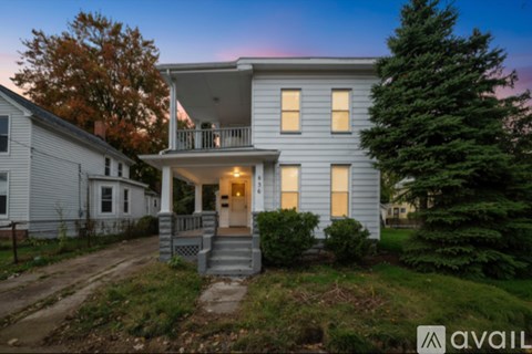 A house with a porch and a tree in front of it.