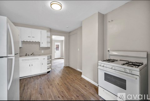 A kitchen with white appliances and wooden floors.