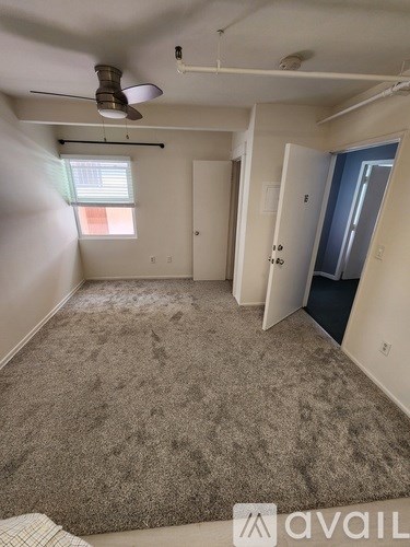 A room with a carpeted floor and a ceiling fan.