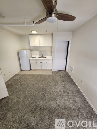 A room with a carpeted floor and a ceiling fan.