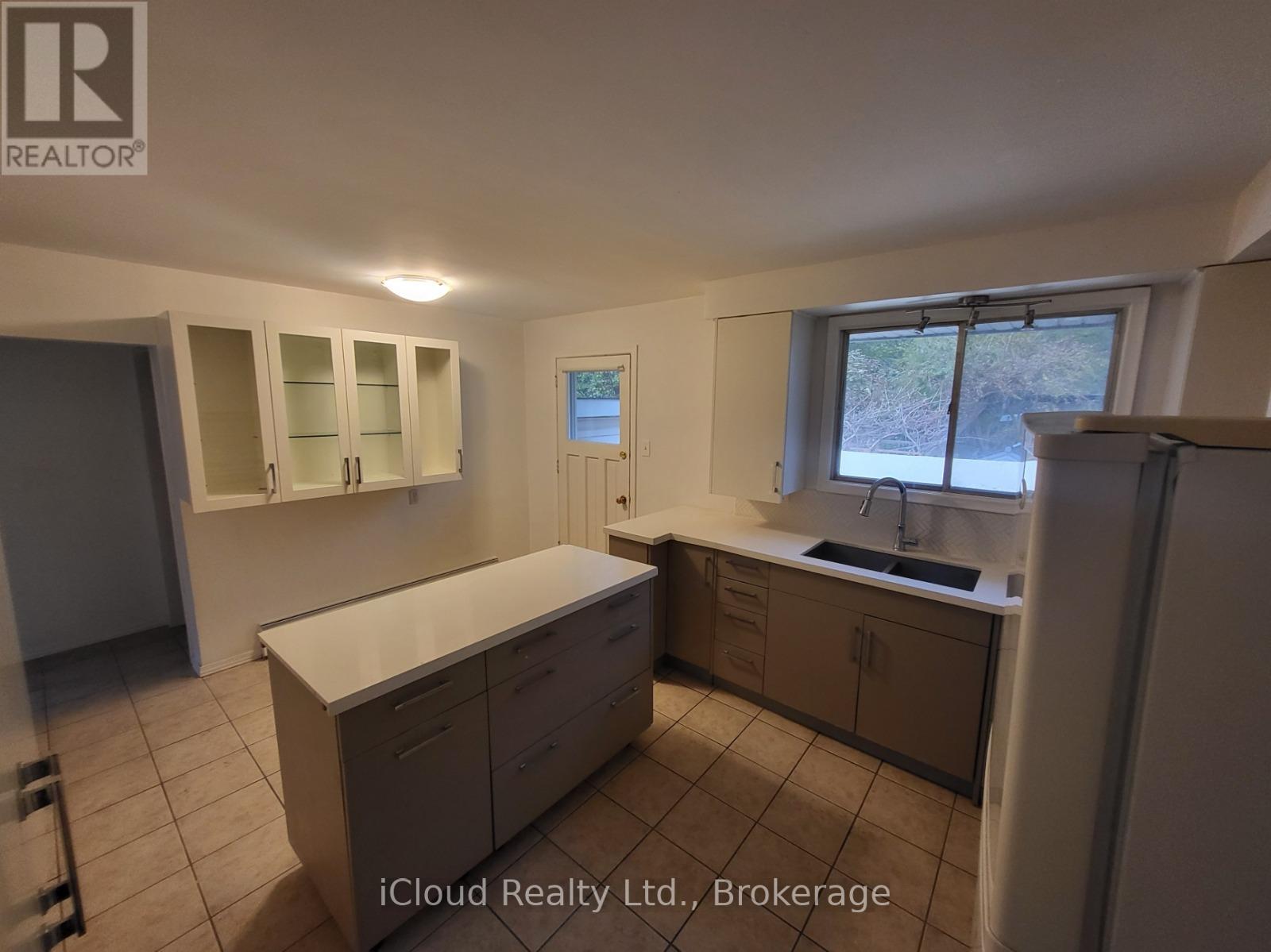 A kitchen with white cabinets and a window overlooking a road.