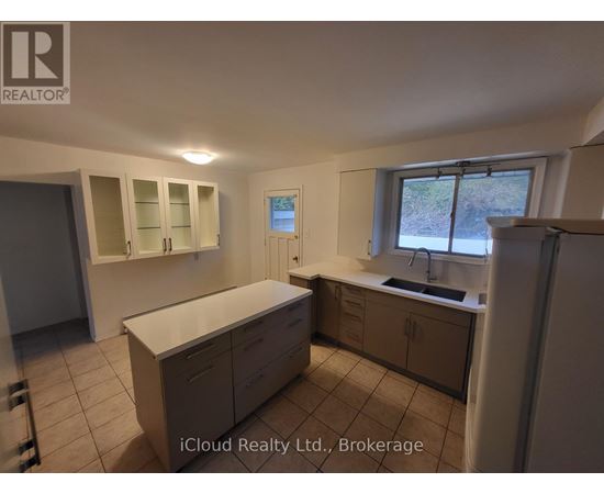 A kitchen with white cabinets and a window overlooking a road.