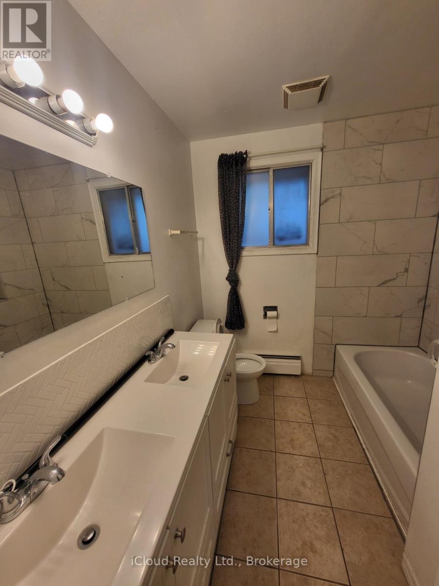 A bathroom with a tub, sink, toilet and mirror.
