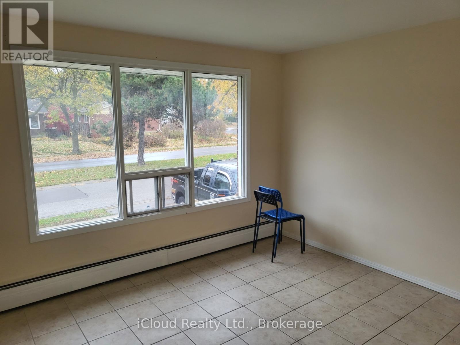 A room with a blue chair and a window overlooking a street.