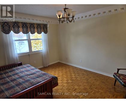 A bedroom with a bed, a bench, and a window with curtains.