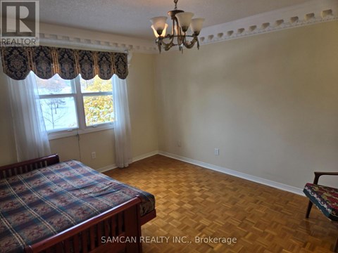 A bedroom with a bed, a bench, and a window with curtains.