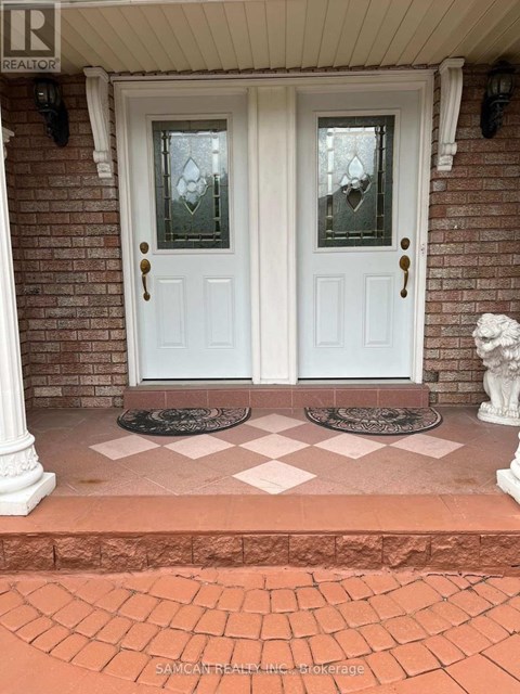 A white double door with glass panels and sidelights is set in a brick wall.
