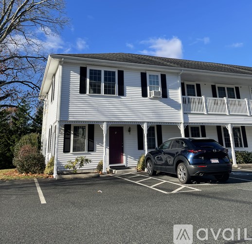 A blue car is parked in front of a white house.