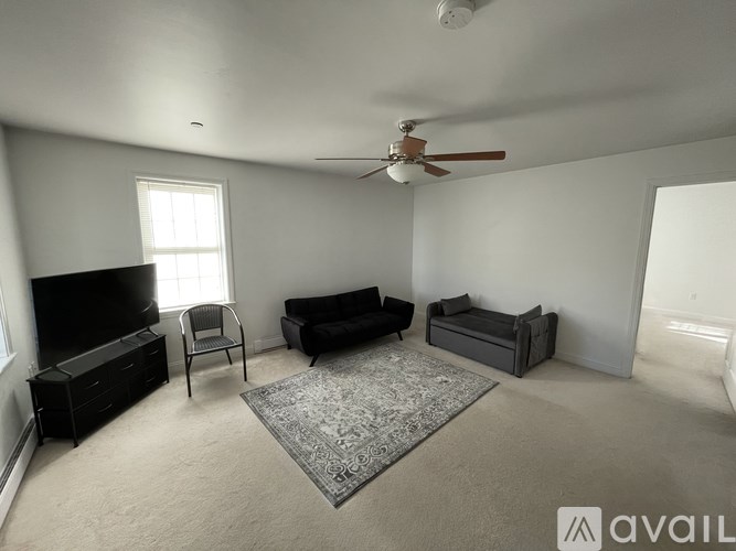 A living room with a television, a chair, a couch, and a rug.