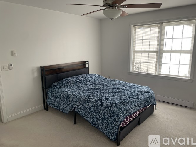 A bedroom with a bed, a ceiling fan, and a window.