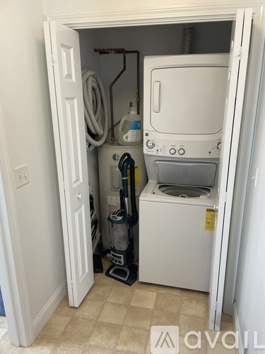 A small white washing machine is in a doorway.