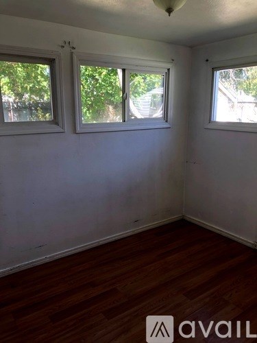 A room with wooden floors and three windows.