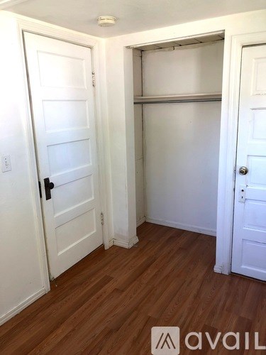 A room with a white door and a wooden floor.