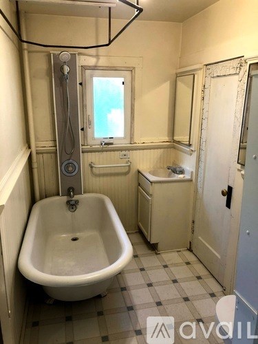 A white bathroom with a claw foot tub and a window.