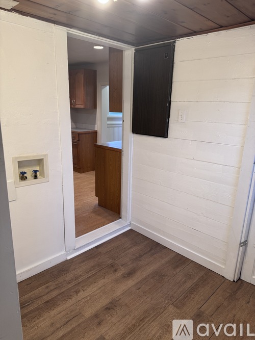 A room with a white wall and wooden floor with a black object on it.