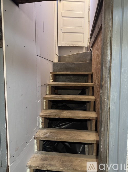 A set of wooden stairs with a plastic bag at the bottom.